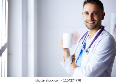 Young Doctor With Coffee Cup In Medical Office