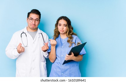 Young doctor couple posing in a blue background isolated showing that she has no money.