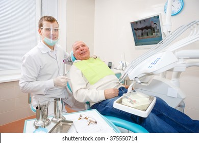 Young doctor dentist and old senior man patient, smiling and looking at the camera in dental office. Health and white tooth - medical care