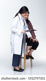 Young Doctor Examines Elderly Asian Woman And Health Check Up On Paper Chart With Stethoscope And Pressure With Smiling Care. Full Length Body Isolated White Background