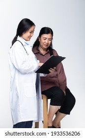 Young Doctor Examines Elderly Asian Woman And Health Check Up On Paper Chart With Stethoscope And Pressure With Smiling Care. Half Body Isolated White Background