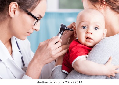 Young doctor examining baby boy with otoscope - Powered by Shutterstock