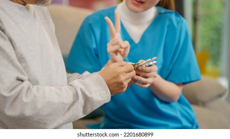 Young Doctor Examining Senior Patient At Home Visit, Senior Man Consulting Medicine With Pharmacist, Caregiver Nurse Taking Care Of Elderly Grandfather Sitting On Sofa At Home, Medical Service Concept