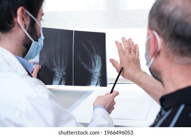 Young doctor examining x-ray of hands of a senior patient with arthritis. Radiography of a hand. - Powered by Shutterstock