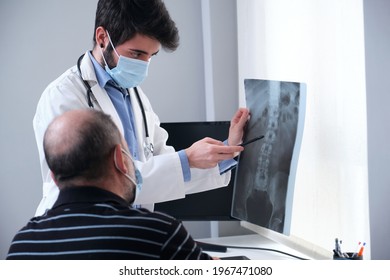 Young doctor examining x-ray of a senior patient backbone. Radiography of a spine, spinal or vertebral column.