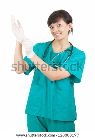 young doctor in green workwear pulling on surgical gloves, white background