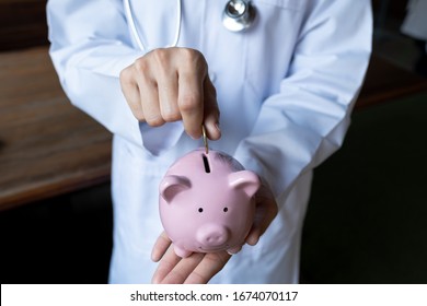 Young doctor hand putting coins into pink piggy bank, saving for retirement and health insurance concept.