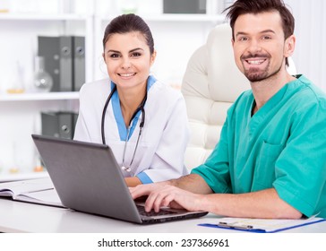 The Young Doctor And His Assistant In A Medical Office At Work With Laptop.