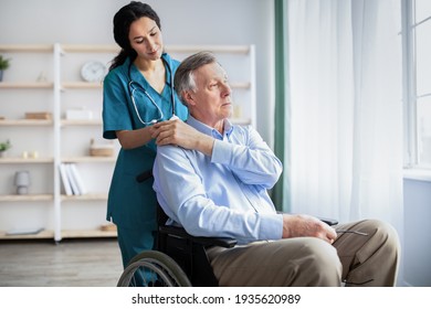 Young doctor holding elderly disabled male's hand, giving him support at retirement home