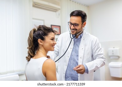 Young Doctor Listen To Female Patient Heart Chest With Stethoscope At Clinic Meeting. Man GP Checkup Examine Woman Client With Phonendoscope. Healthcare Concept.