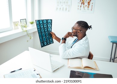 Young Doctor Looking At Computed Tomography X-ray Image. Confident Pleasant Doctor Working With MRI Scan Results. Radiologist Man Checking X-ray, Health Care, Medical And Radiology Concept