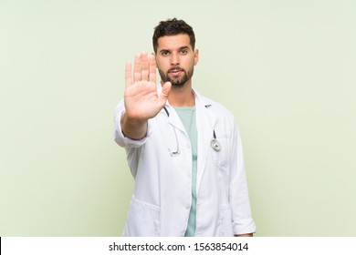 Young Doctor Man Over Isolated Green Wall Making Stop Gesture With Her Hand