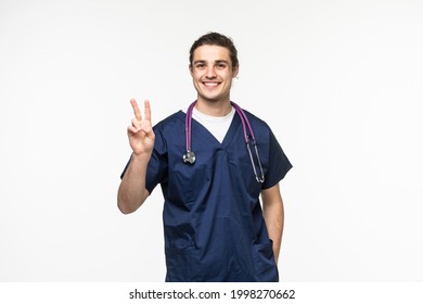 Young doctor man wearing medical coat and stethoscope over isolated background smiling showing fingers doing victory sign. Number two.