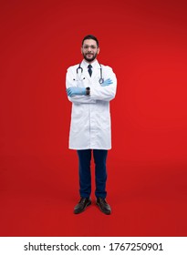 Young doctor man wearing stethoscope  and blue gloves standing over isolated red background. - Shutterstock ID 1767250901