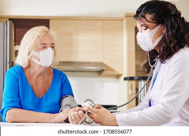 Young Doctor In Medical Mask Checking Blood Pressure Of Senior Patient During Pandemic Period