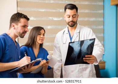 Young Doctor And Medical Residents Analyzing X-rays Of A Patient In A Hospital Room