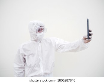 Young Doctor Or Scientist In PPE Suite Uniform While Using His Phone For Selfie And Video Chats With Family Or Freind. Coronavirus Or COVID-19 Concept Isolated White Background