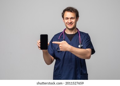 Young Doctor Showing A Phone And Pointing Isolated On White Background