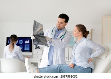 Young doctor showing x-ray image of spine to patient in clinic - Powered by Shutterstock