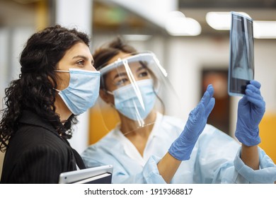 Young doctor shows an X-ray photograph of lungs to the patient and explains the diagnosis. Coronavirus prevention and prophylaxy. Hospital and medicine concept