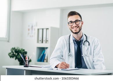 Young Doctor Sitting In His Office Behind A Desk