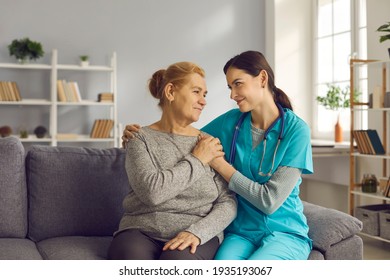 Young doctor supporting senior woman. Friendly nurse or clinician and happy older adult patient sitting on sofa, looking at each other, holding hands and smiling. Health check, trust and care concept