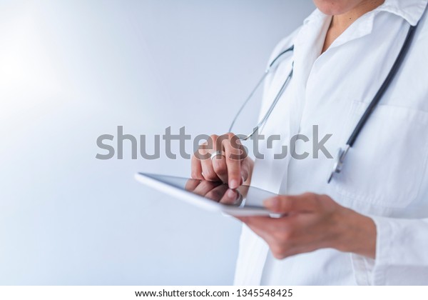 Young\
doctor using digital tablet against dental equipment.\
Unrecognizable Doctor using digital tablet in hospital. Global\
Technology in Healthcare And Medicine Concept .\
