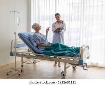 Young Doctor Visit The Ward And Talking To Older Female Patient And Note The Information To Chart For Diagnosis.