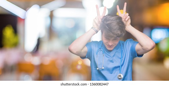 Young doctor wearing medical uniform over isolated background Posing funny and crazy with fingers on head as bunny ears, smiling cheerful - Powered by Shutterstock