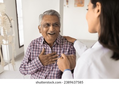 Young doctor woman calming senior Indian patient, holding mans hand, touching shoulder with comfort, support, compassion, telling good news about health, heart work - Powered by Shutterstock