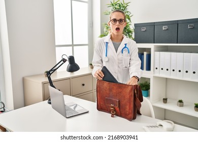 Young Doctor Woman At The Clinic In Shock Face, Looking Skeptical And Sarcastic, Surprised With Open Mouth 