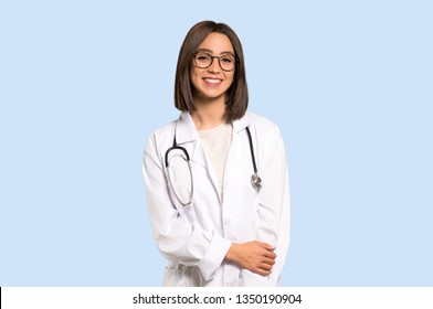 Young doctor woman with glasses and happy on isolated blue background