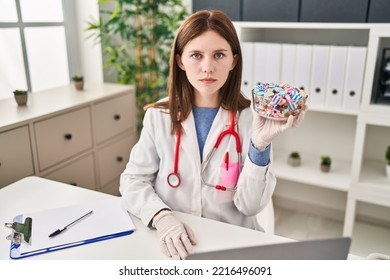 Young Doctor Woman Holding Sweets Candy Thinking Attitude And Sober Expression Looking Self Confident 