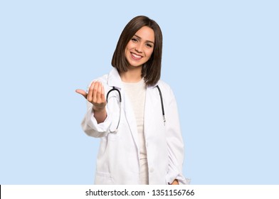 Young doctor woman inviting to come with hand. Happy that you came on isolated blue background - Powered by Shutterstock