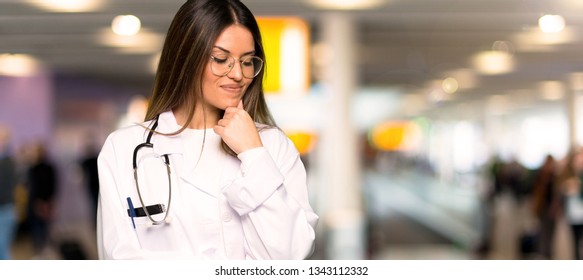 Young Doctor Woman Looking Down With The Hand On The Chin In A Hospital