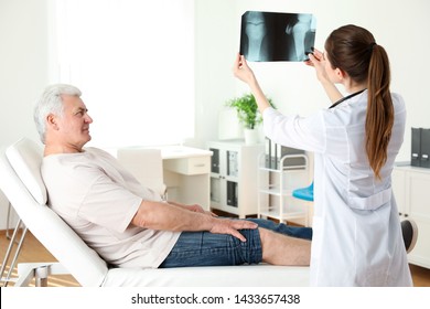 Young doctor with X-ray and senior patient in clinic. Knee problem