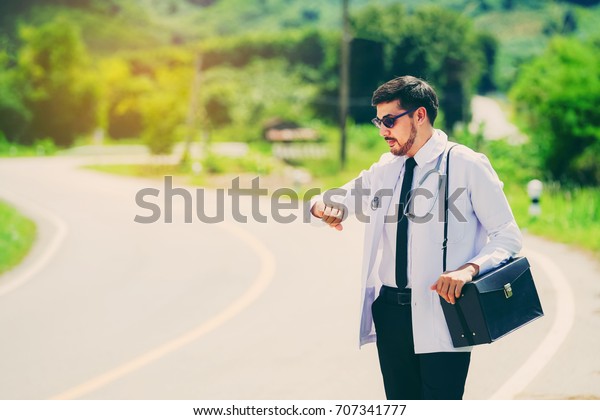 Young doctors check the time waiting for the\
hospital car to travel to treat the patient. Rural doctor concept\
\
                             \
