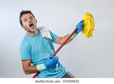 Young Domestic Service Man Or Happy Husband Cleaning Home Playing With Mop A Song On Air Guitar Having Fun Enjoying Isolated On Even Background In Housekeeping And Home Cleaning Concept