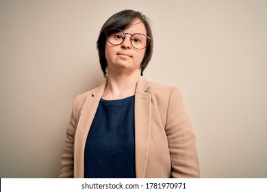 Young down syndrome business woman wearing glasses standing over isolated background Relaxed with serious expression on face. Simple and natural looking at the camera.