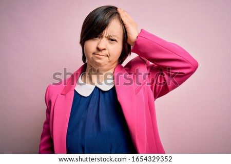 Young down syndrome business woman over pink background confuse and wonder about question. Uncertain with doubt, thinking with hand on head. Pensive concept.