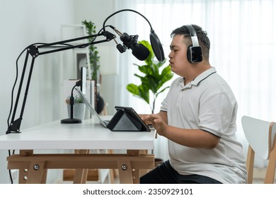 Young down syndrome DJ man wearing headphone and speak on microphone at studio. Teenager patient person feeling happy and relax while recording news podcast show for radio broadcasting at home studio. - Powered by Shutterstock