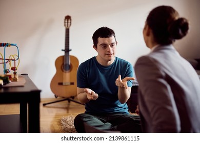 Young Down Syndrome Man Learning To Count On His Fingers With Help Of A Tutor At Home.