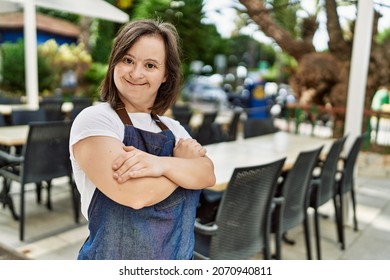 Young-down-Syndrom-Frau lächelt selbstbewusst mit Schürze auf der Terrasse des Cafés