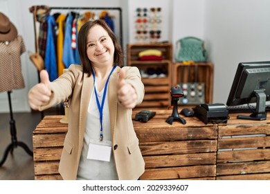 Young Down Syndrome Woman Working As Manager At Retail Boutique Approving Doing Positive Gesture With Hand, Thumbs Up Smiling And Happy For Success. Winner Gesture. 