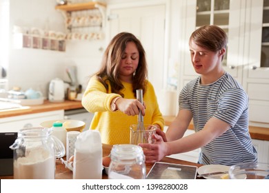 Young Downs Syndrome Couple Baking In Kitchen At Home