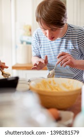 Young Downs Syndrome Man Baking Cupcakes In Kitchen At Home