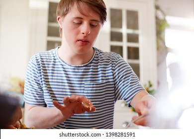 Young Downs Syndrome Man Baking Cupcakes In Kitchen At Home