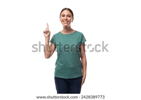 young dreamy beautiful brunette lady with ponytail hairstyle dressed in green t-shirt and jeans holding thumbs up [[stock_photo]] © 