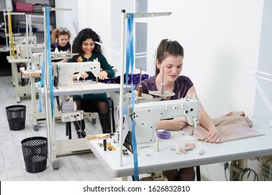 Young dressmaker women sew clothes on sewing machine in tailor studio