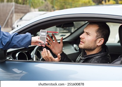 Young Driver Arguing With A Police Officer During Test For Alcohol Content With Breathalyzer, He Is Angry And Not Willing To Participate With Police Officer 